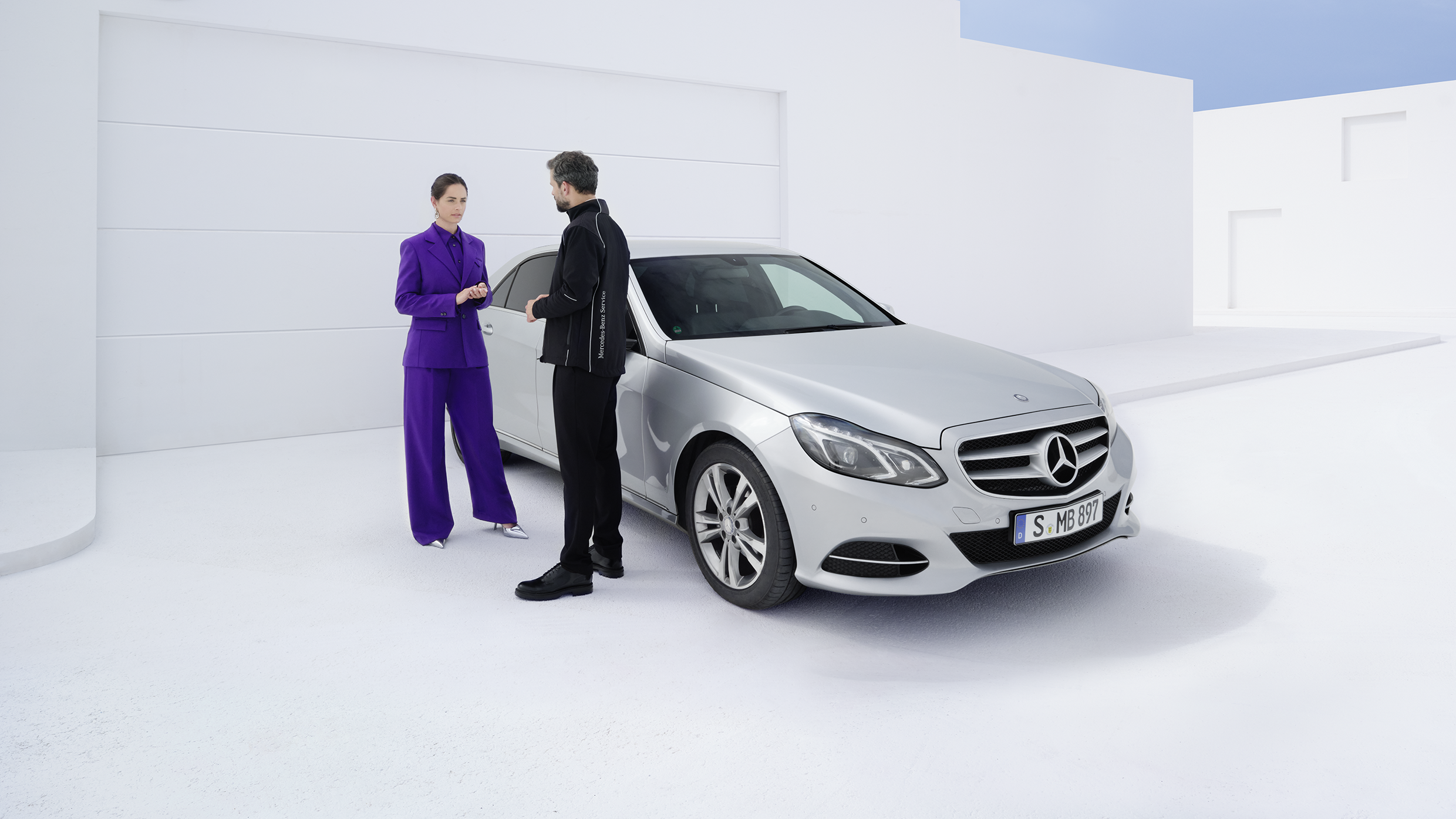 Kaksi henkilöä Mercedes-Benz E-sarjan vieressä.